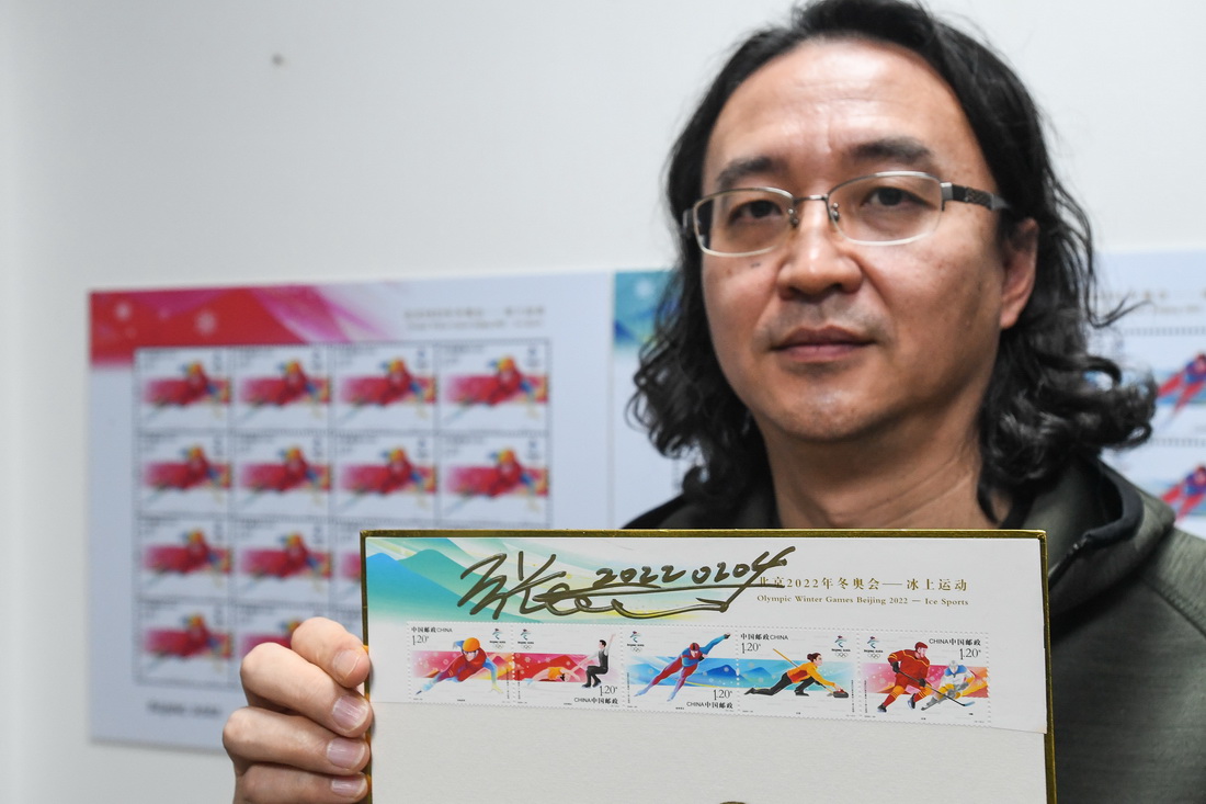 设计师张强展示他设计的北京2022年冬奥会冰上运动纪念邮票（2月8日摄）。