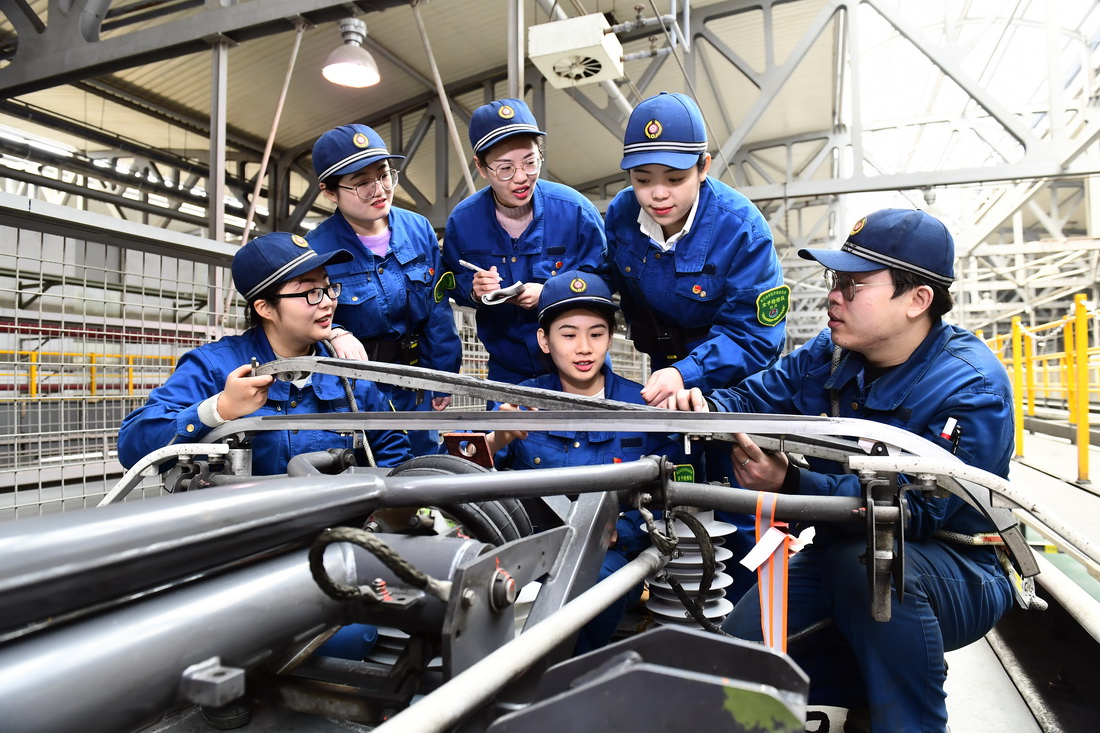 2月10日，在国铁济南局青岛动车段济南动车所，四星级机械师宋昊（右一）在教检修队员们更换碳滑板。